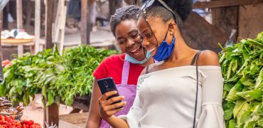 The two women viewing content on a phone in a local African market.